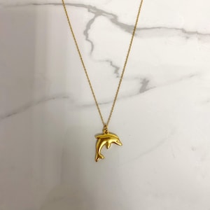 May include: A gold chain necklace with a gold dolphin pendant.