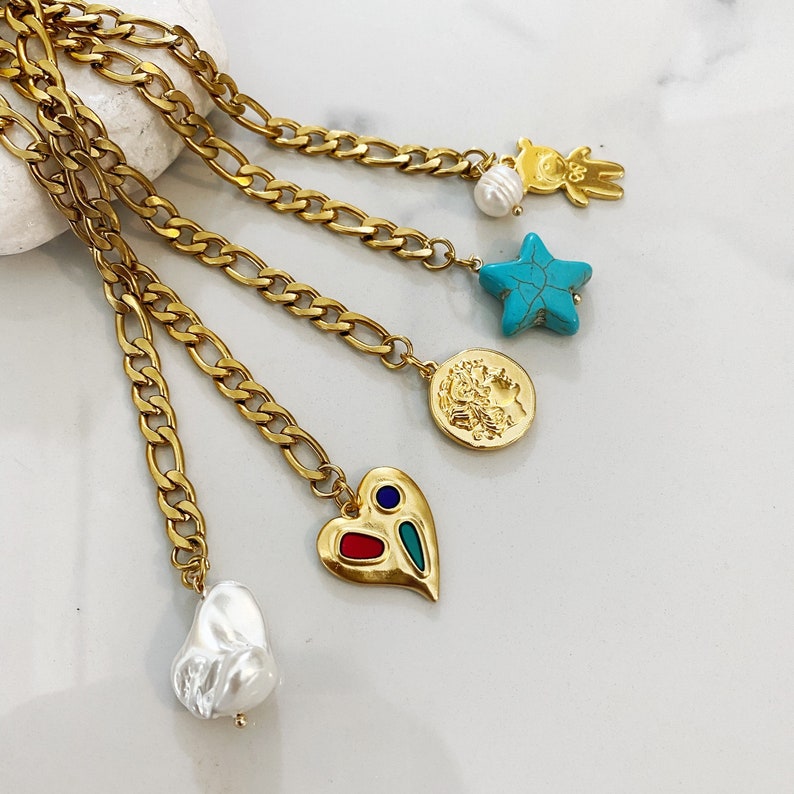 May include: Gold chain necklace with multiple charms, including a heart, a star, a coin, and a pearl. The charms are made of gold and have colorful accents.