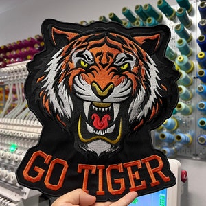 May include: A black and orange embroidered patch with a tiger face and the text "GO TIGER".