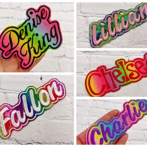 May include: A collection of embroidered name patches in various colors. The names "Denise King", "Lillian", "Chelsea", "Fallon", and "Charlie" are displayed in a stylized font with a rainbow gradient effect.