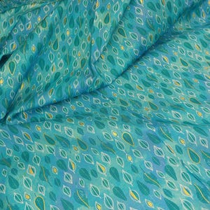 May include: Teal fabric with a repeating pattern of gold and white leaves. The fabric has a subtle watercolor effect.