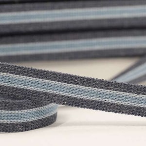 May include: Gray and light blue striped woven ribbon. The ribbon is made of a textured fabric and has a subtle sheen.
