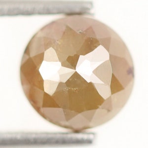 Op de afbeelding: Een ronde, gefacetteerde, bruine diamant edelsteen vastgehouden door een pincet.