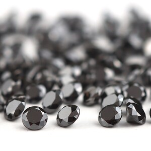 May include: A pile of black diamonds, also known as carbonado diamonds, on a white background.