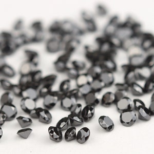 May include: A scattering of black diamonds on a white surface. The diamonds are round and have a brilliant cut.