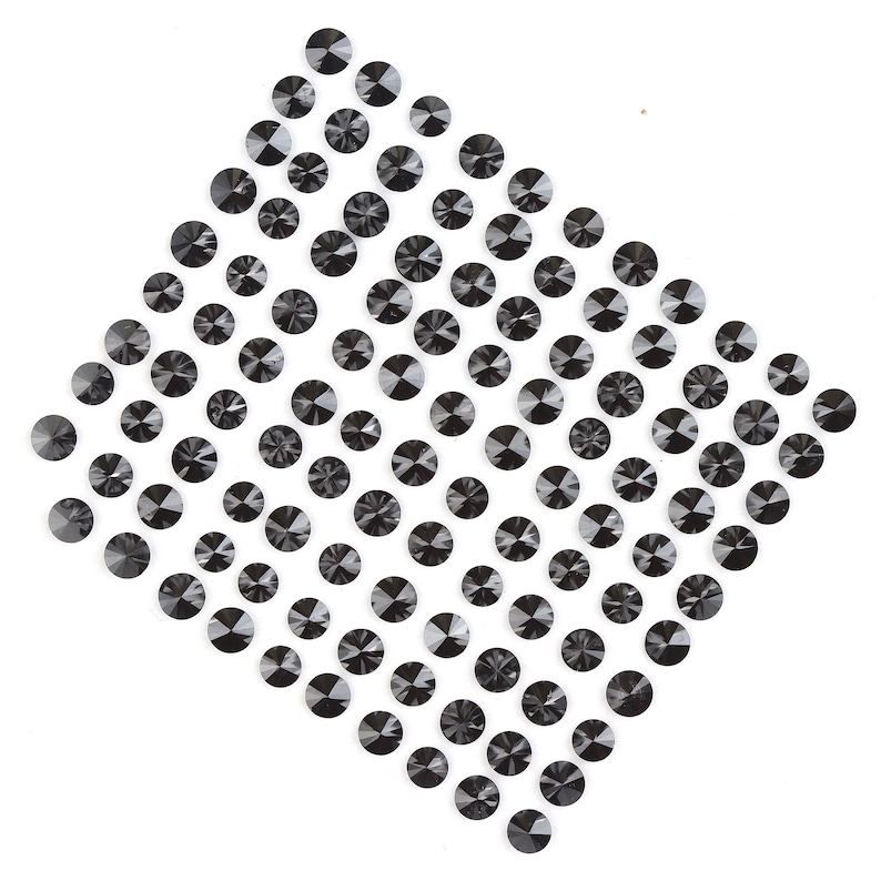 May include: A diamond-shaped arrangement of black rhinestones on a white background.