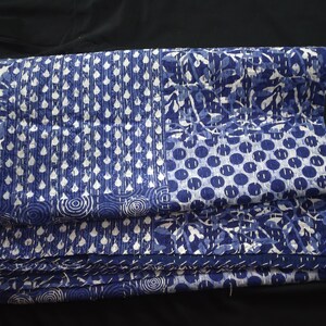 Puede incluir: Una colcha kantha azul y blanca con una variedad de patrones, incluyendo c&iacute;rculos, puntos y hojas. La colcha est&aacute; doblada en tres partes y est&aacute; hecha de algod&oacute;n.