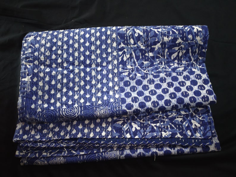 Puede incluir: Una colcha kantha azul y blanca con una variedad de patrones, incluyendo c&iacute;rculos, puntos y hojas. La colcha est&aacute; doblada en tres partes y est&aacute; hecha de algod&oacute;n.