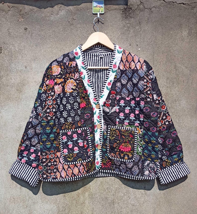 May include: A black quilted jacket with a floral patchwork design. The jacket has a button closure, two pockets, and a striped lining.