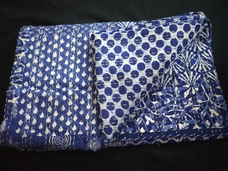 Puede incluir: Una colcha kantha azul y blanca con una variedad de patrones, que incluyen lunares, hojas y espirales.