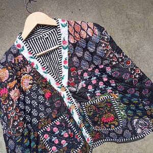 May include: A black quilted jacket with a floral print and a button closure. The jacket is made of patchwork fabric with different patterns and colors.