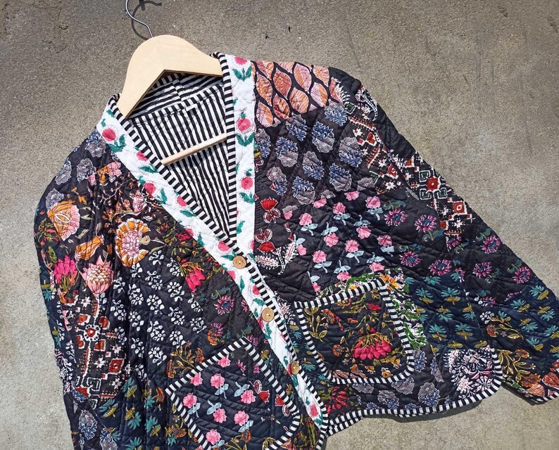 May include: A black quilted jacket with a floral print and a button closure. The jacket is made of patchwork fabric with different patterns and colors.
