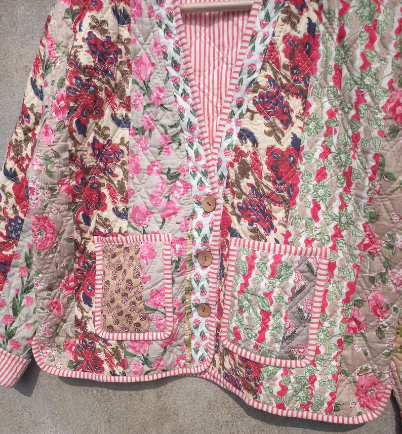 May include: A quilted jacket with a floral print in shades of pink, red, and green. The jacket has a V-neck, two pockets, and a button closure.