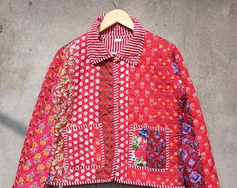 May include: A red quilted jacket with a patchwork design. The jacket has a button closure and a collar. The fabric is a mix of floral and geometric patterns.