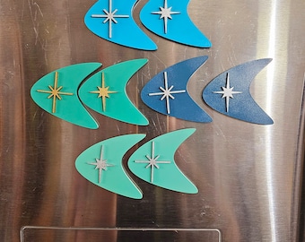 May include: Six retro-style boomerang-shaped magnets with a starburst design in various colors, including teal, turquoise, and green. The magnets are attached to a stainless steel refrigerator with a red "Smile More" logo.