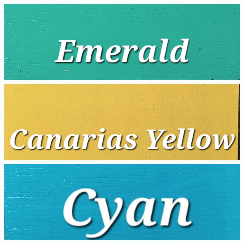 Op de afbeelding: Drie verfkleuren met de namen "Emerald", "Canarias Yellow" en "Cyan" in wit.