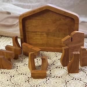 May include: Wooden nativity set with a brown wooden stable and a variety of wooden animal figurines, including a camel, sheep, and cows.