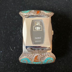 May include: A silver watch with a turquoise and orange design. The watch face is black with a digital display and the text "Sheffield Swiss Made T".