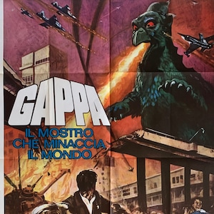 May include: A movie poster for the Japanese kaiju film "Gappa: The Triphibian Monster". The poster features a green, reptilian monster with a long, pointed beak, breathing fire. The monster is standing in front of a destroyed city, with people running away in fear. The poster also features the title of the film in large, white letters, and the names of the actors and director in smaller letters.