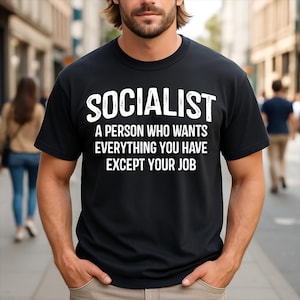 May include: A black short-sleeved crew neck t-shirt featuring white text that reads: SOCIALIST A PERSON WHO WANTS EVERYTHING YOU HAVE EXCEPT YOUR JOB. The lettering is printed in a bold, sans-serif font across the chest of the garment.