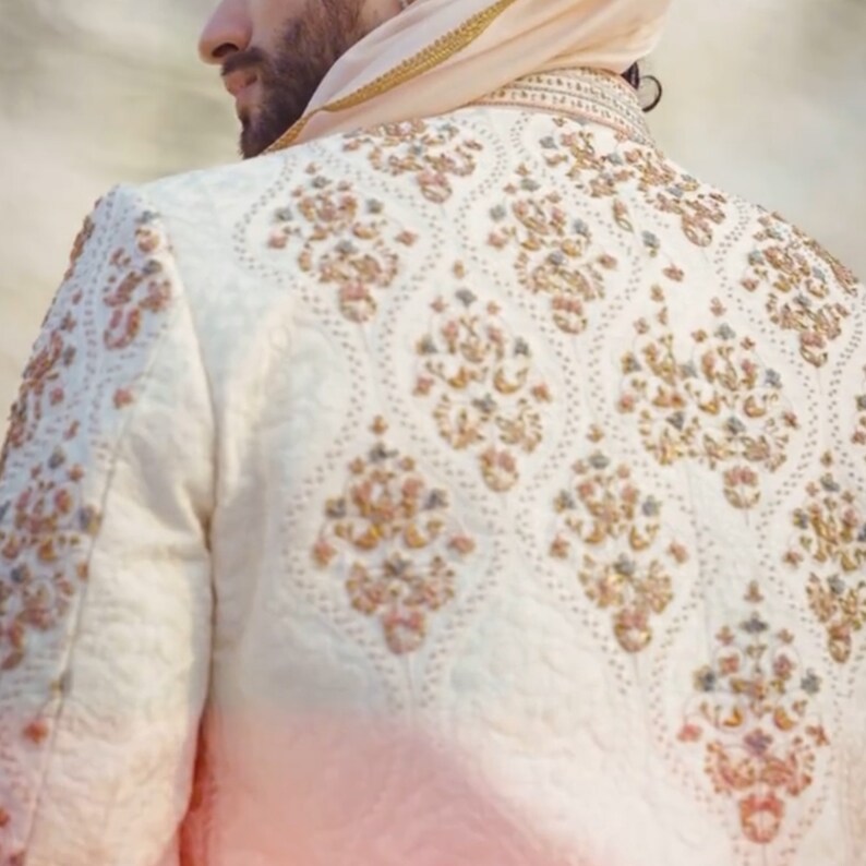 May include: White embroidered jacket with a detailed floral pattern in shades of pink, gold, and blue.