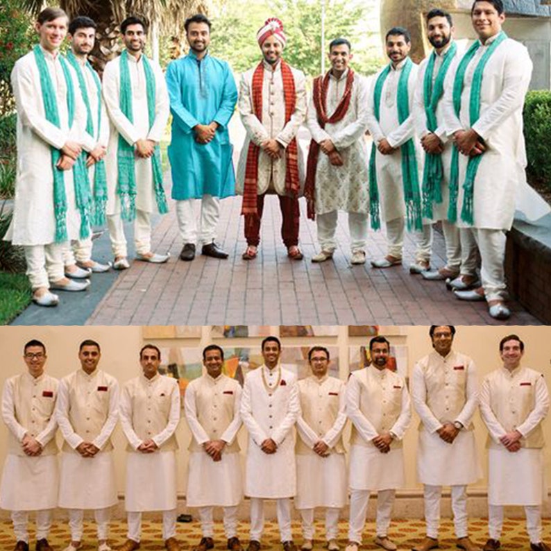 May include: Two groups of men wearing traditional Indian clothing. The first group is wearing white kurtas with teal scarves, while the second group is wearing white kurtas with beige vests. All of the men are smiling and looking at the camera.