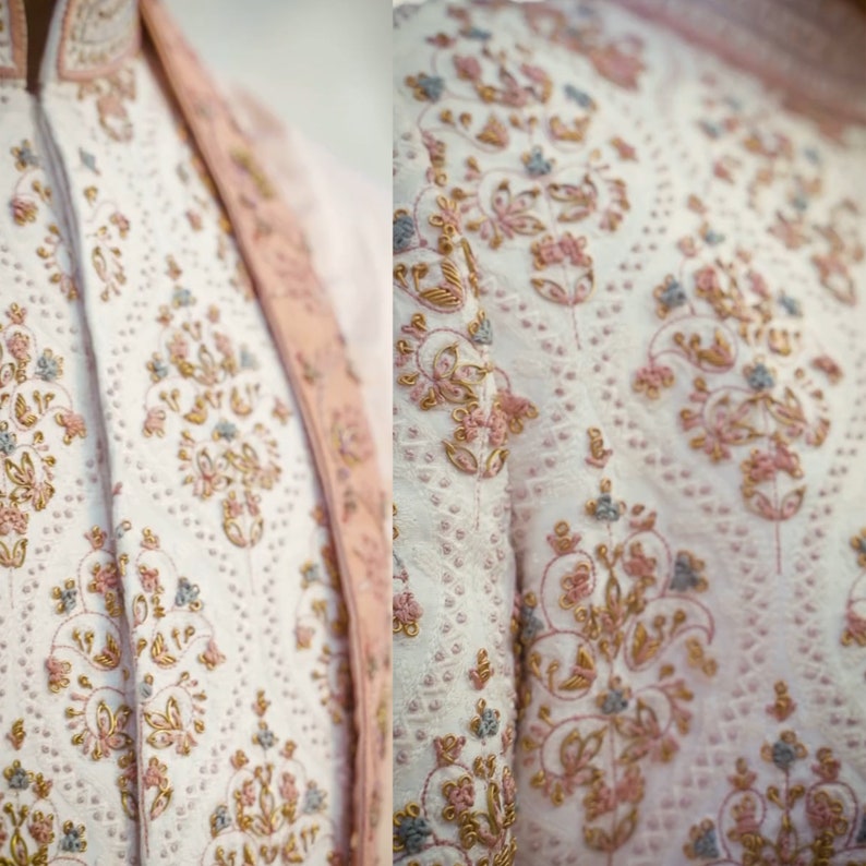 May include: White fabric with intricate floral embroidery in shades of pink, gold, and blue. The embroidery features delicate floral patterns and swirls.