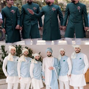 May include: A group of men wearing traditional Indian wedding attire. The men are wearing green kurtas with white pants and white turbans. They are also wearing gold jewelry and flowers in their hair. The men are standing in a line and smiling.