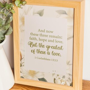 Peut inclure: Une impression encadrée avec un motif floral et une inscription dorée qui dit "Et maintenant il reste ces trois choses : la foi, l'espérance et l'amour. Mais le plus grand de ces trois, c'est l'amour. 1 Corinthiens 13:13"