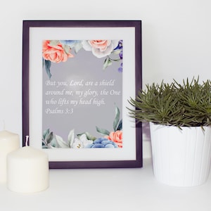Puede incluir: Una impresión enmarcada con un diseño floral de acuarela y un versículo bíblico, "Pero tú, Señor, eres un escudo a mi alrededor, mi gloria, el Único que levanta mi cabeza en alto. Salmos 3:3", sobre un fondo gris.