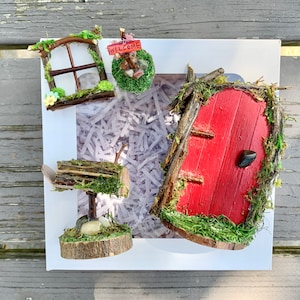 Geschenkset voor een sprookjesdeur. Wordt geleverd met een rode sprookjesdeur, een welkomstbordje in de sprookjestuin, een sprookjestuinraam en een sprookjestuinbrievenbus.