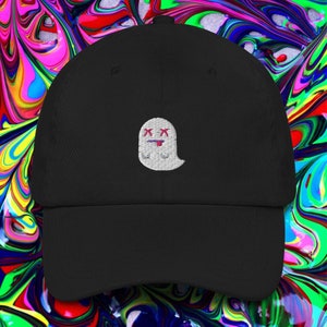 May include: Black baseball cap featuring a white embroidered ghost design. The ghost has crossed-out eyes and a lolling tongue. The cap is made of a soft fabric and has a curved peak.