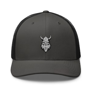 Op de afbeelding: Een donkergrijze truckercap met een zwart mesh-achterpaneel. De pet heeft een geborduurd wit Vikinghoofd met een gehoornde helm.