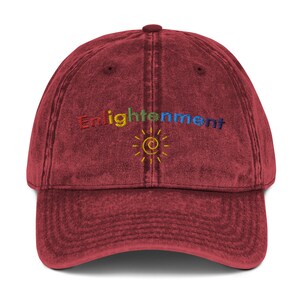 K&ouml;nnte beinhalten: Eine rote Vintage-Baseballkappe mit dem Wort "Enlightenment" in Regenbogenfarben gestickt und einer gelben Sonne mit einem blauen Kreis in der Mitte.