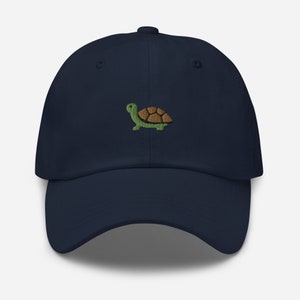Peut inclure: Une casquette de baseball bleu marine avec un motif de tortue verte brodé.