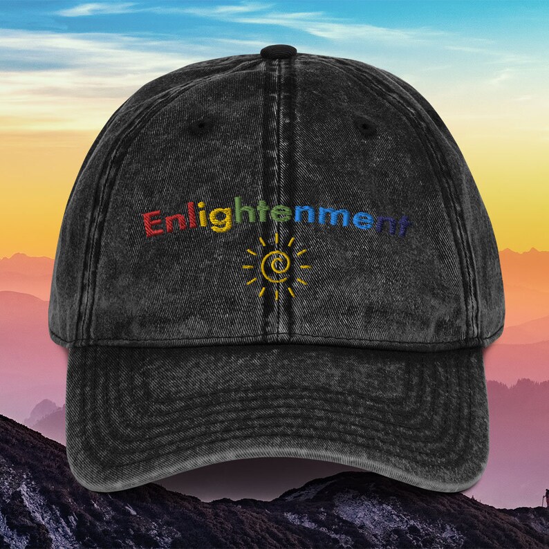 K&ouml;nnte beinhalten: Schwarze Baseballkappe im Vintage-Stil mit dem in Regenbogenfarben gestickten Wort "Enlightenment" und einer gelben Sonne mit einem Wirbel in der Mitte.