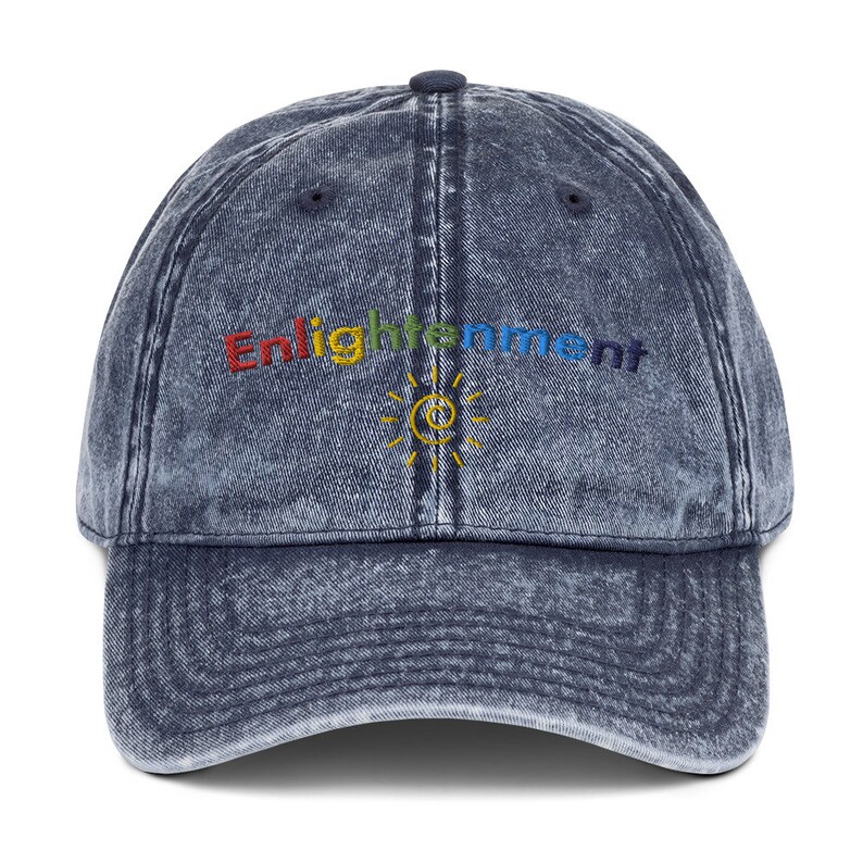 K&ouml;nnte beinhalten: Eine blaue Denim-Baseballkappe mit Used-Look. Die Kappe hat ein regenbogenfarbenes gesticktes Logo mit der Aufschrift "Enlightenment" und einem Sonnensymbol.