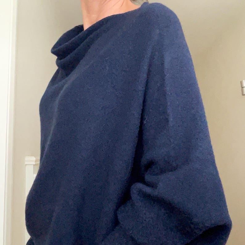 May include: A navy blue cowl neck sweater with long sleeves.
