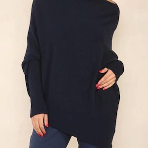 May include: A navy blue, long-sleeved, oversized sweater with a draped neckline and asymmetrical hem.
