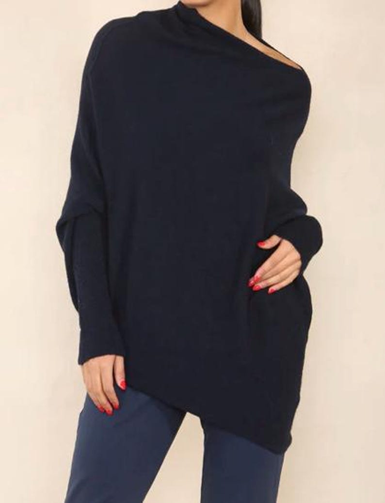May include: A navy blue, long-sleeved, oversized sweater with a draped neckline and asymmetrical hem.