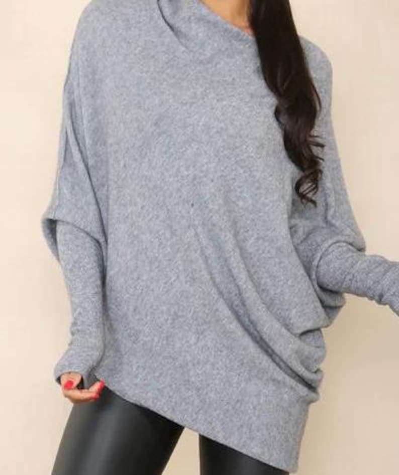 May include: A gray, long-sleeved, oversized sweater with a cowl neck and thumbholes.