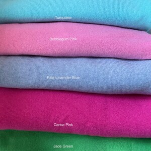 May include: Five fabric swatches stacked on top of each other. The swatches are turquoise, bubblegum pink, pale lavender blue, cerise pink, and jade green.