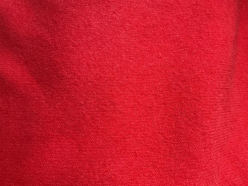 May include: A close-up of a solid red fabric with a slightly textured surface.