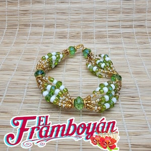 May include: A beaded bracelet with green, white, and gold beads. The bracelet has a gold clasp and is made with multiple strands of beads. The image also includes the text "El Flamboyán" in a decorative font.