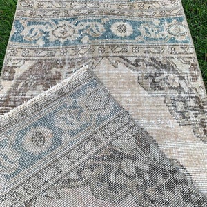 May include: A vintage rug with a faded blue and brown pattern. The rug is made of a soft, woven material and has a distressed look.