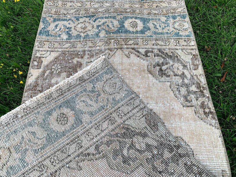 May include: A vintage rug with a faded blue and brown pattern. The rug is made of a soft, woven material and has a distressed look.