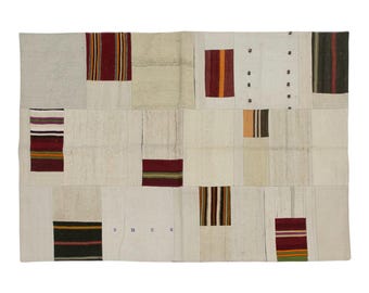 Puede incluir: Alfombra rectangular de patchwork con fondo crema y varios parches rectangulares. Los parches presentan rayas en rojo, naranja, marrón y verde. La alfombra tiene una estética vintage y artesanal.