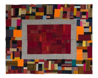 May include: A rectangular patchwork rug with a central red rectangle framed by a gray border. The rug features a variety of colorful rectangular patches in shades of red, orange, yellow, blue, and brown, creating a vibrant and textured design.