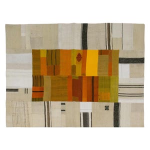 Puede incluir: Una alfombra rectangular de patchwork con un panel central de rectángulos naranjas, amarillos y marrones. Las secciones circundantes son beige con rayas verticales en negro y marrón. Un pequeño patrón de diamantes rojos está en el centro.