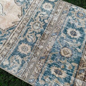 May include: A vintage rug with a blue and beige pattern. The rug has a faded look and is made of a soft, woven material.